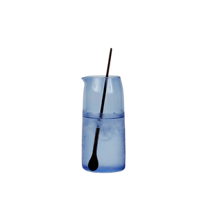 Blue glass with a black spoon inside on a white background