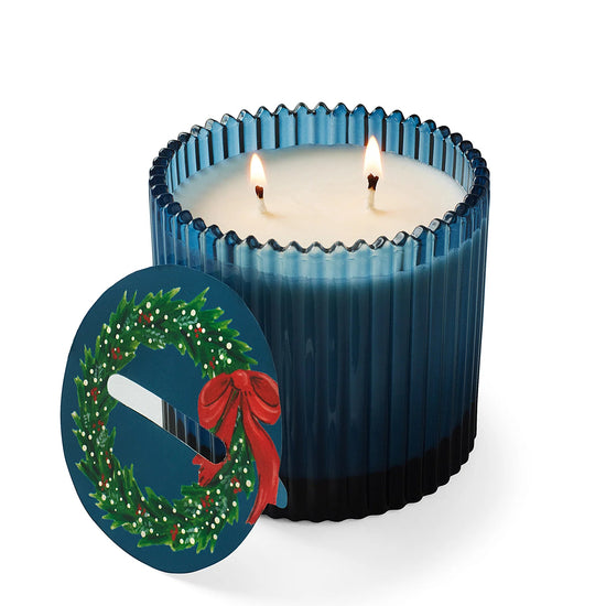 Blue candle with a Christmas wreath design on a white background
