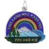 Decorative ornament with rainbow, mountains, trees, and text on a white background