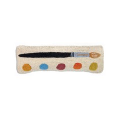 Decorative pillow with a paintbrush and color swatches on a beige background
