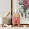 Glass Liquid Soap bottle labeled "Savon Liquide Marseille Extra pur, Rose Sauvage" in front of rose art print and flower petals